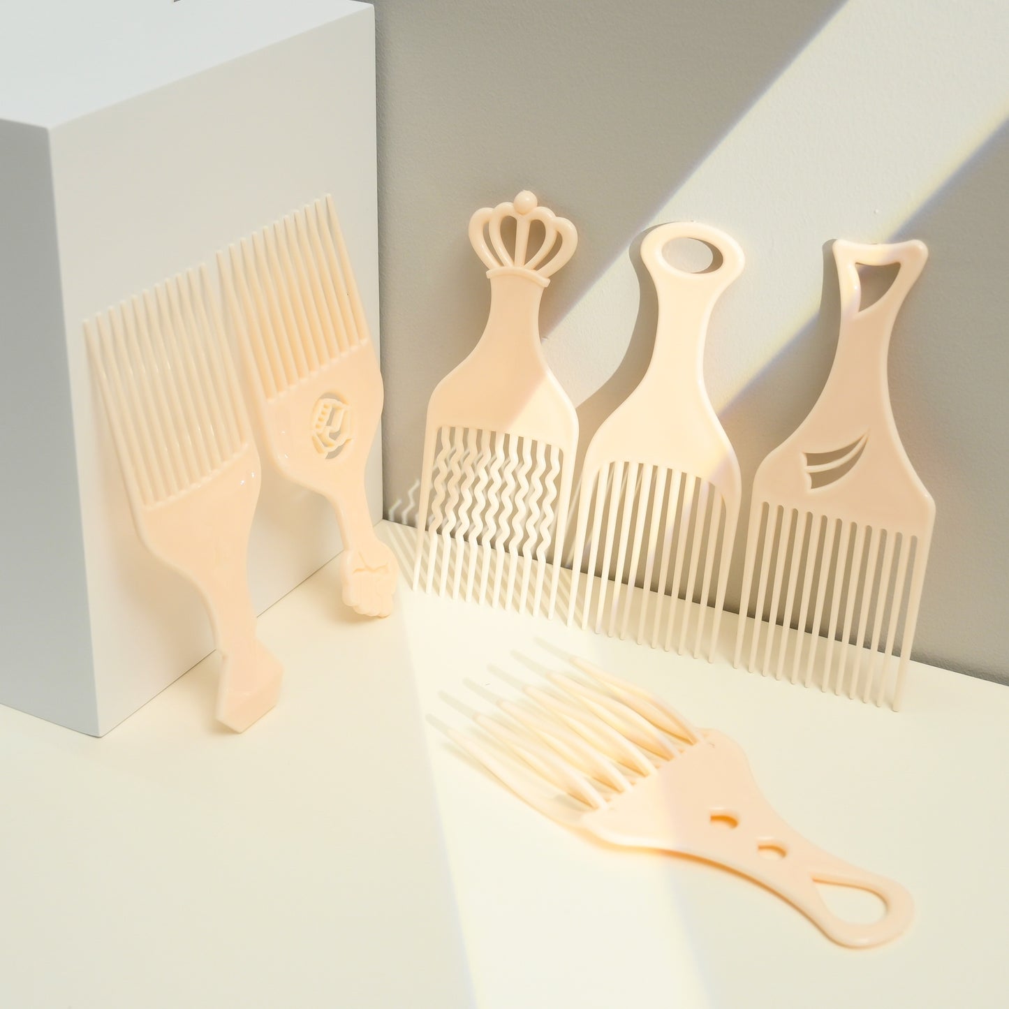 Set of five beige combs with different designs on a light gray background