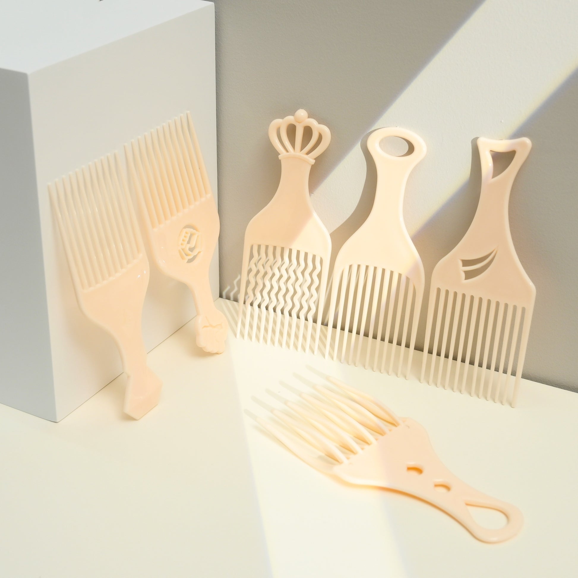 Set of five beige combs with different designs on a light gray background